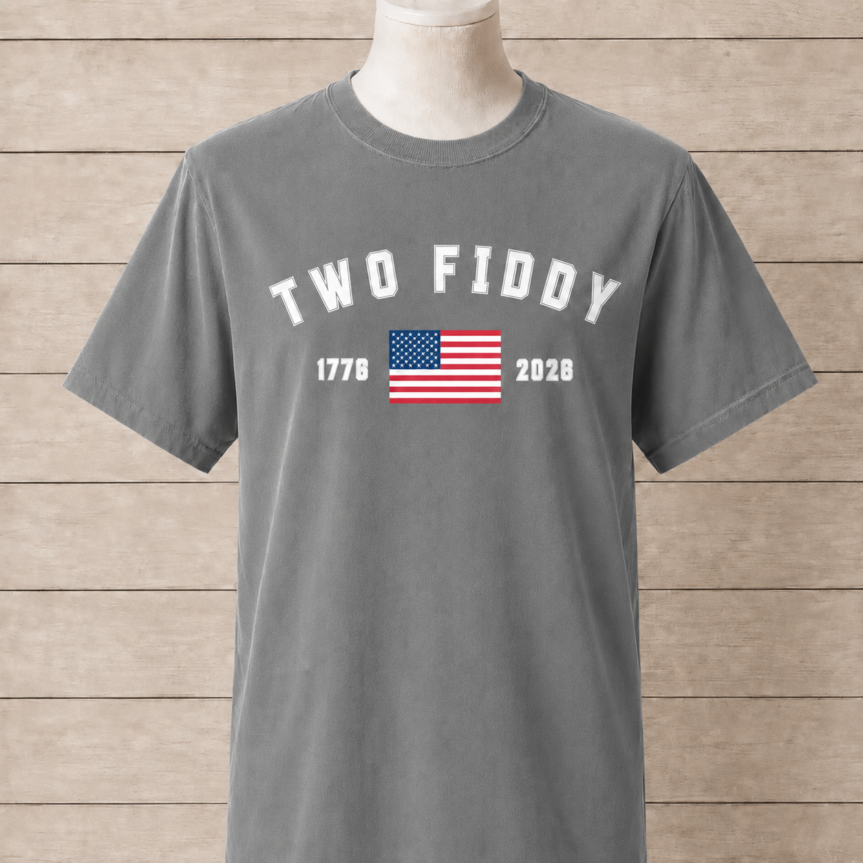 Gray t-shirt with 'TWO FIDDY' text and American flag on a wooden background