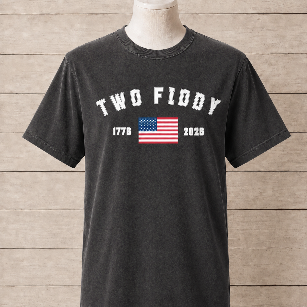 Black t-shirt with 'TWO FIDDY' text and American flag on a wooden background
